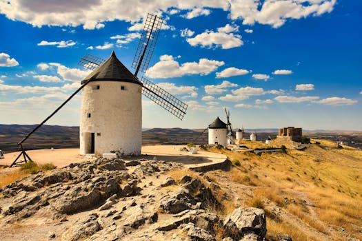 Vista panorámica de molinos de viento tradicionales en Consuegra, España, con un cielo azul brillante.