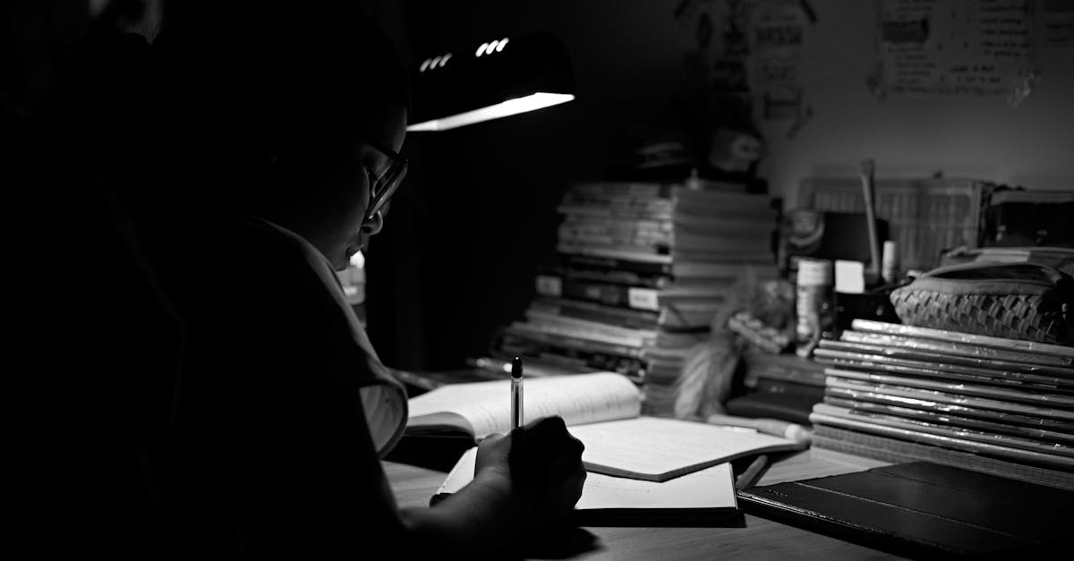 A Woman with Eyeglasses Writing on White Paper Under a Light